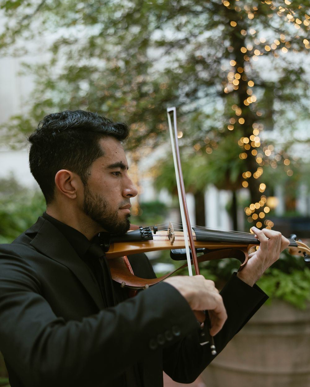 Alejandro López playing violin in a garden courtyard