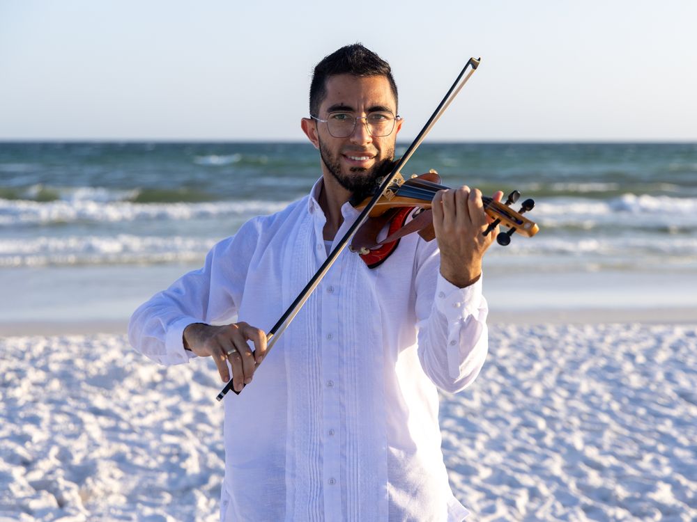 Alejandro playing solo violin on the beach